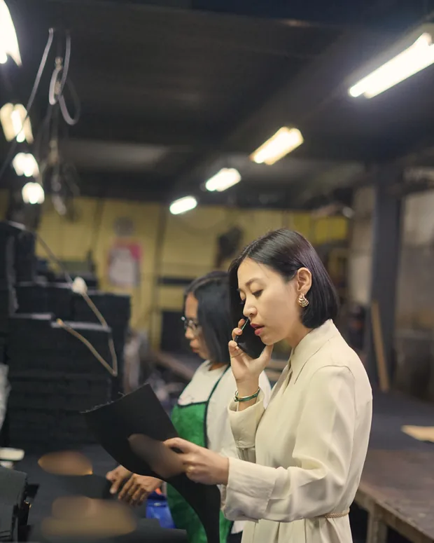 Adinda berkoordinasi lewat telepon di lantai produksi pabrik