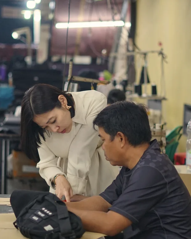 Adinda memeriksa hasil jahitan tas bersama salah satu pengrajin